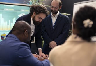 Business partners meeting to share details and exchange impressions about statistics extracted from online research forms. Group collaborating on organizational development plan.