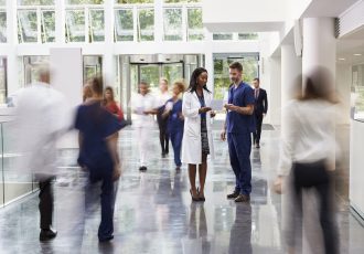 Staff In Busy Lobby Area Of Modern Hospital